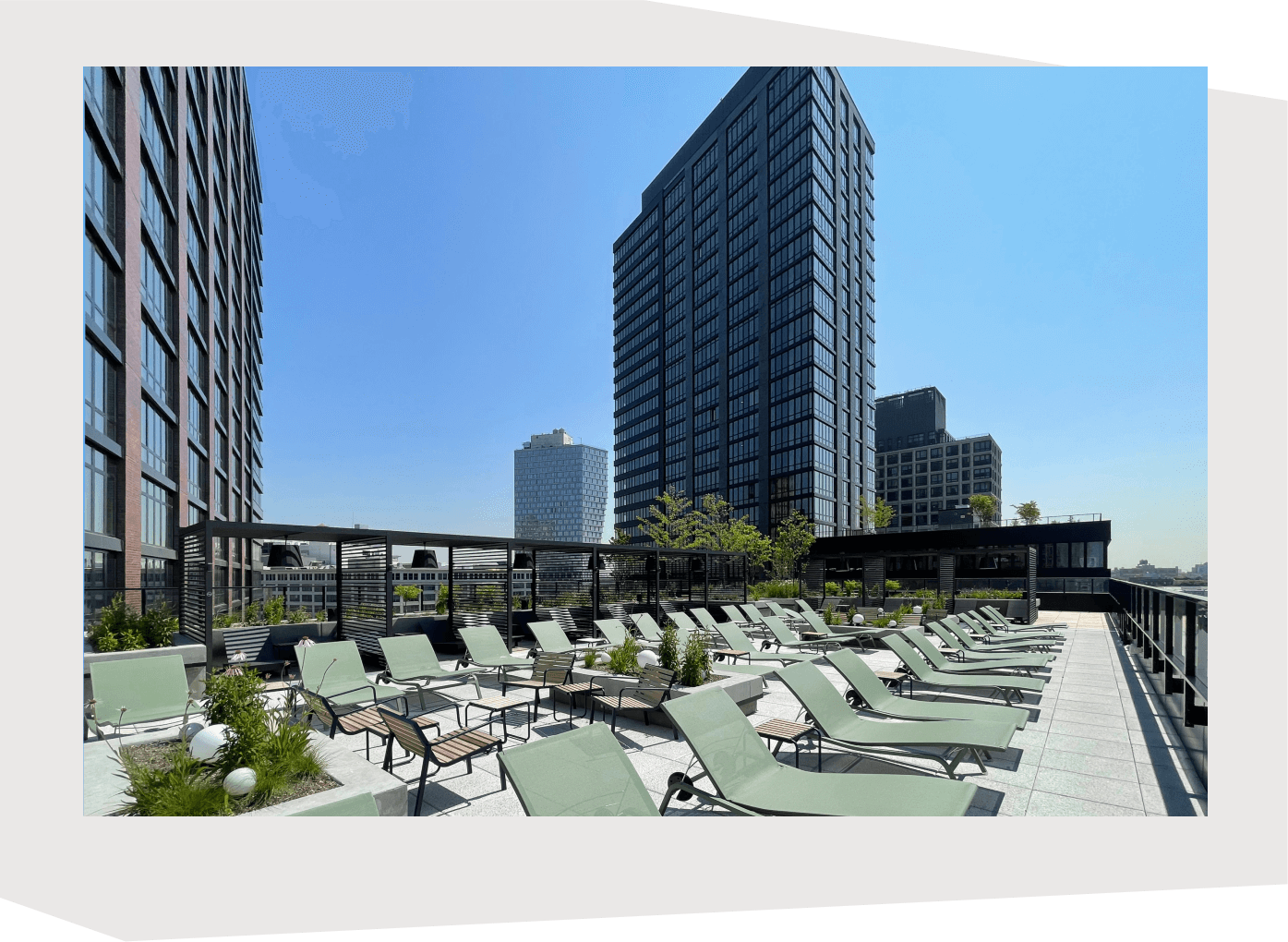 The sundeck of 595 Dean St during the daytime with deck chairs in the foreground and the East Tower and open sky in the background.